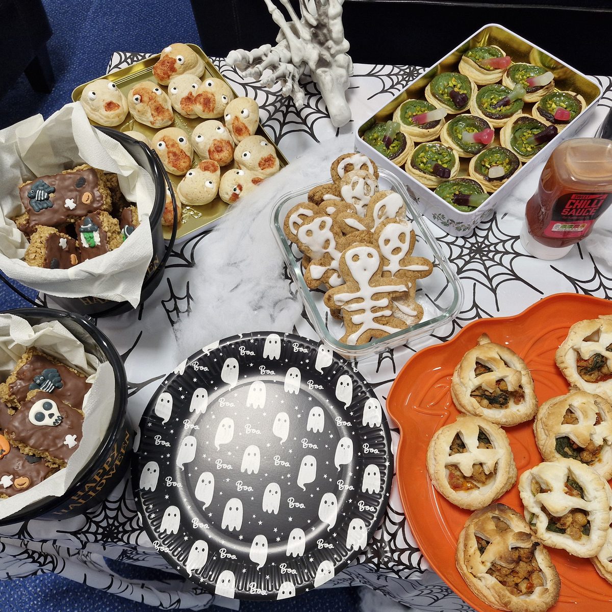 Halloween bake table with skeleton gingerbread men, jack o'lantern pastries, decorated flapjack and ghost plates