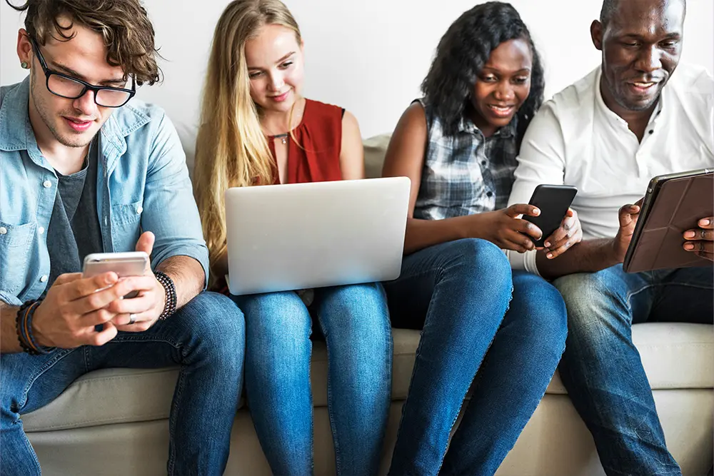 Group of diverse young people using different types of devices