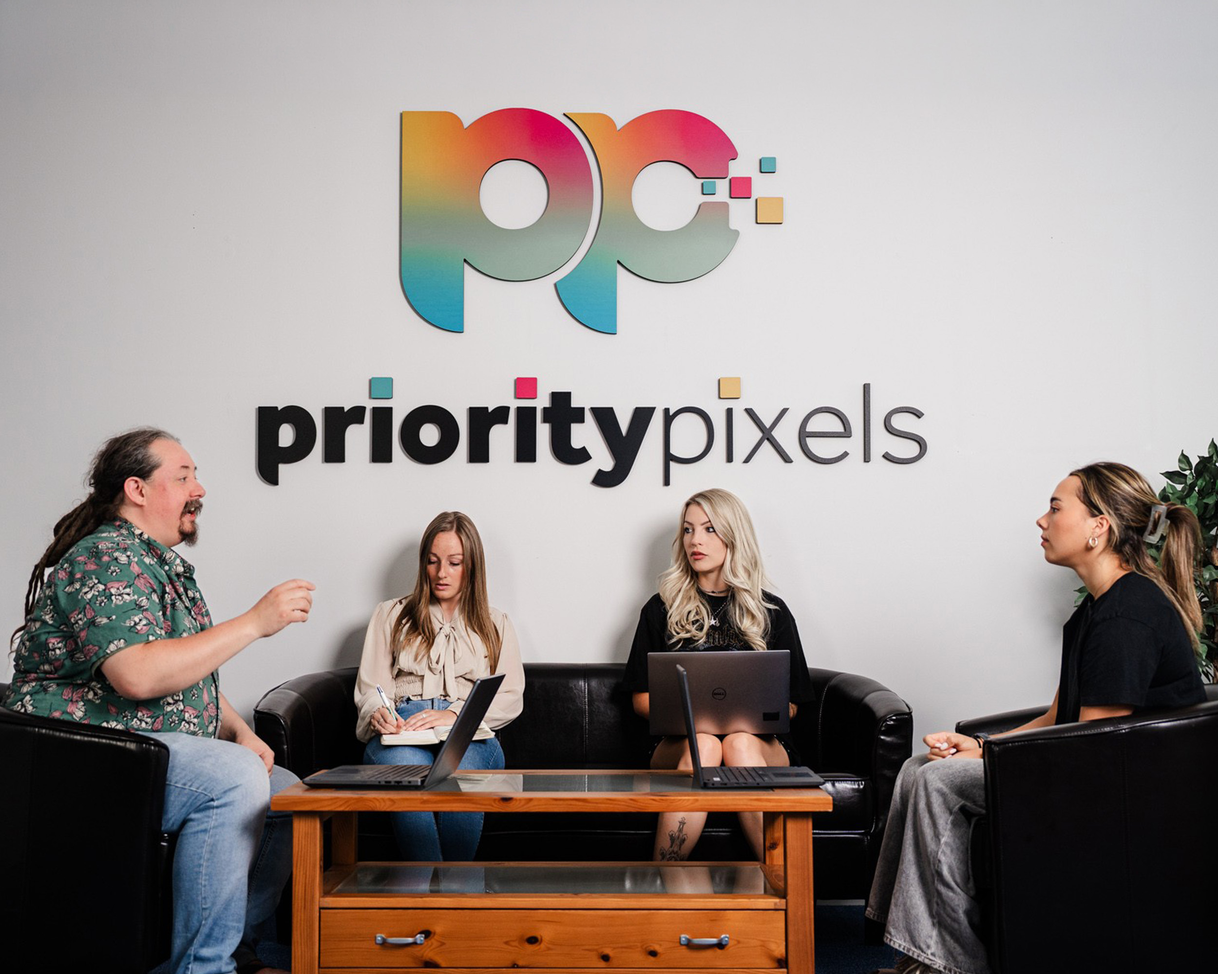 Priority Pixels B2B marketing team in a meeting below the logo