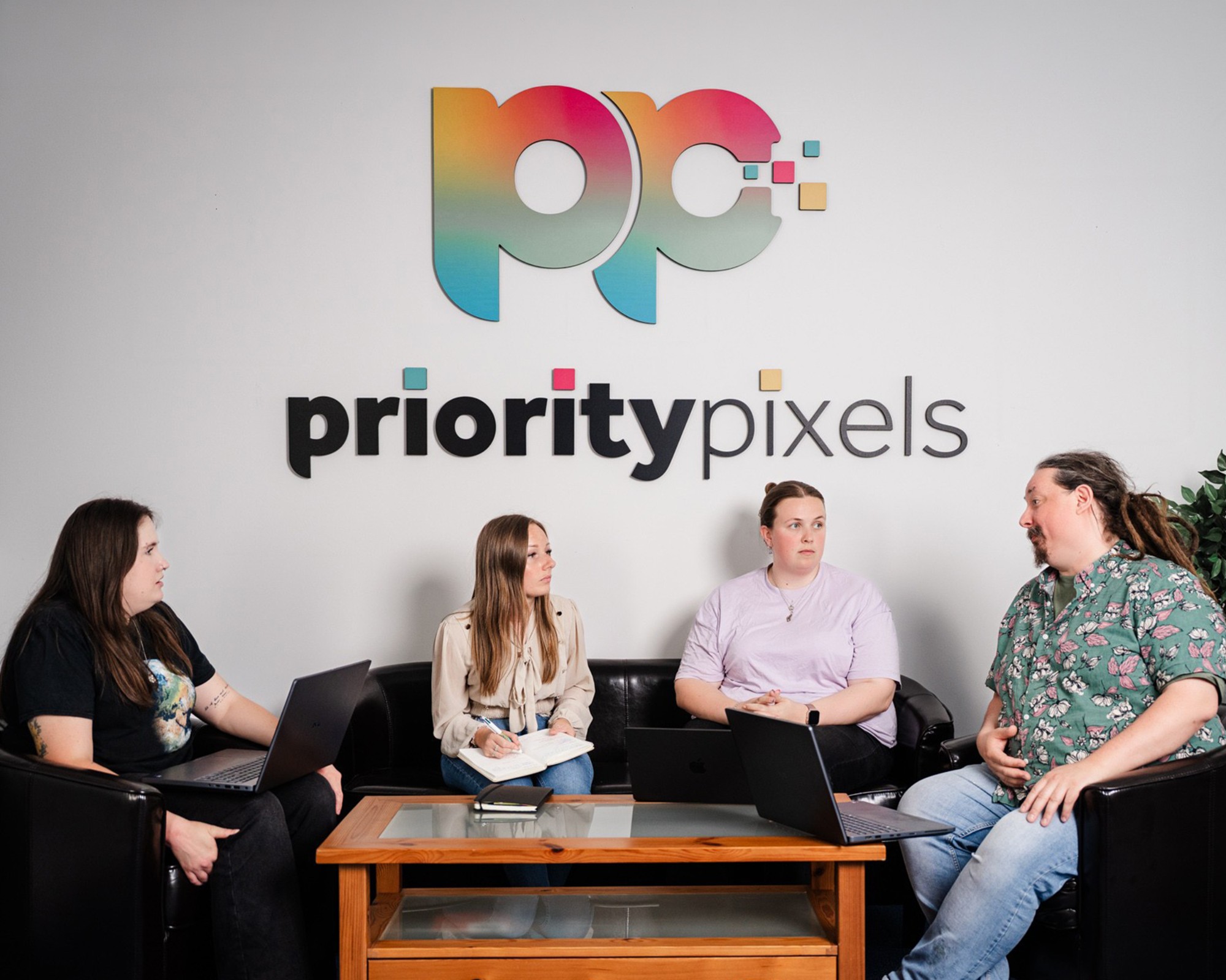 Priority Pixels B2B marketing team in a meeting below the logo